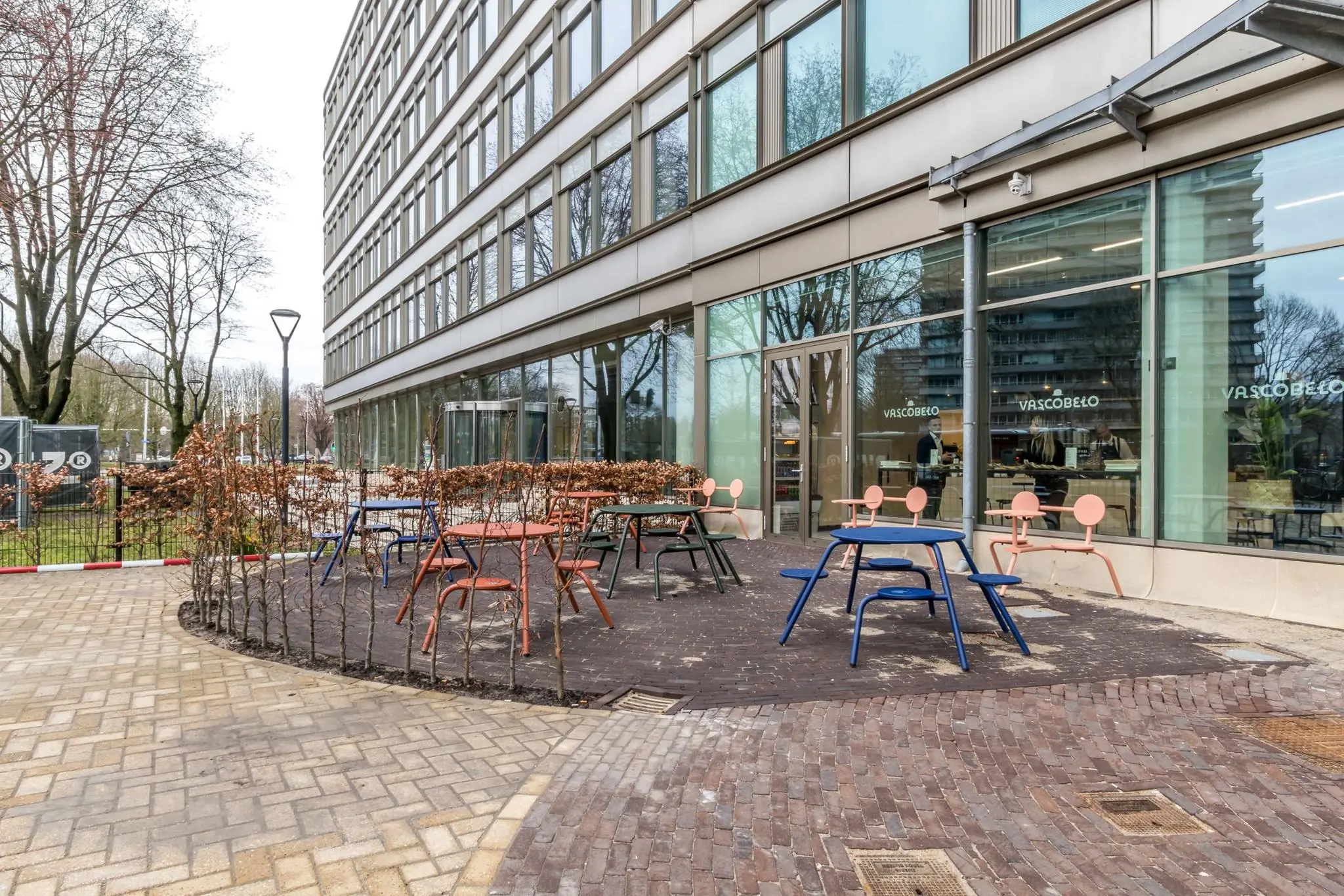 Terras met kleurrijke tafels en stoelen bij café Vascobelo aan de Vliegend Hertlaan.